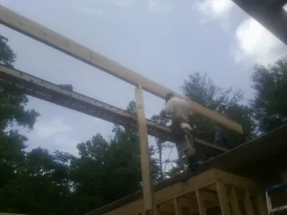 Carpenter setting a ridge beam over a new addition frame — Ice Dam Removal by Roofing Brothers in Melstone