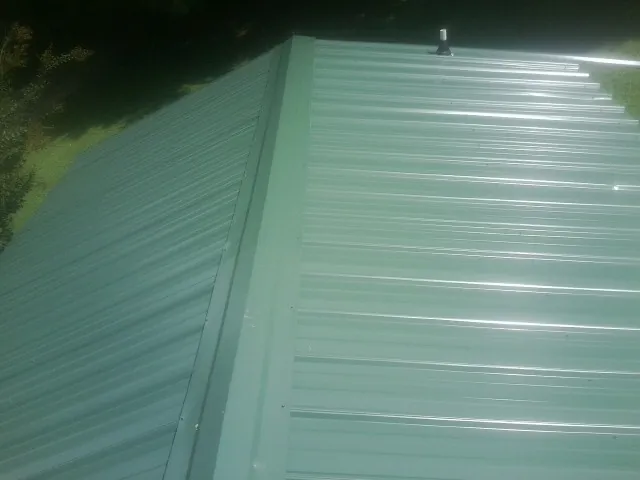 New green metal panels meeting at the ridge of a roof — Flat Roof Repair work by our crew in Melstone