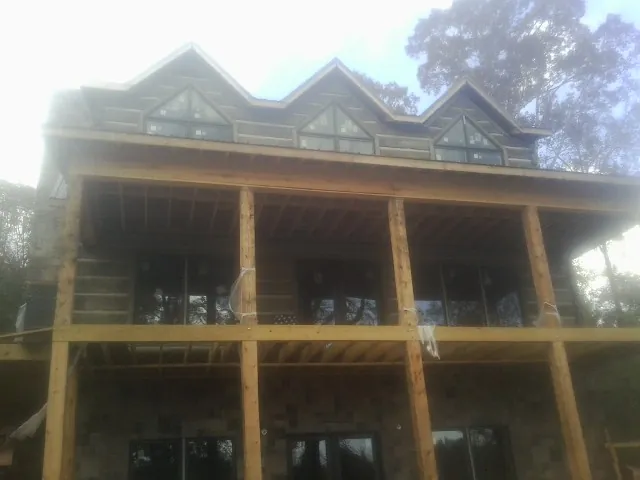 Dormers and porch framing on a large log home under construction — Roof Coating work by our crew in Melstone
