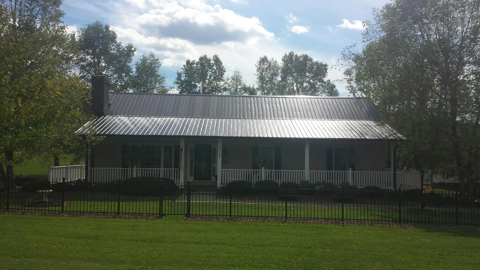 Gray metal roof on a brick ranch with a full width front porch — Gutter Guard Installation work by our crew in Melstone