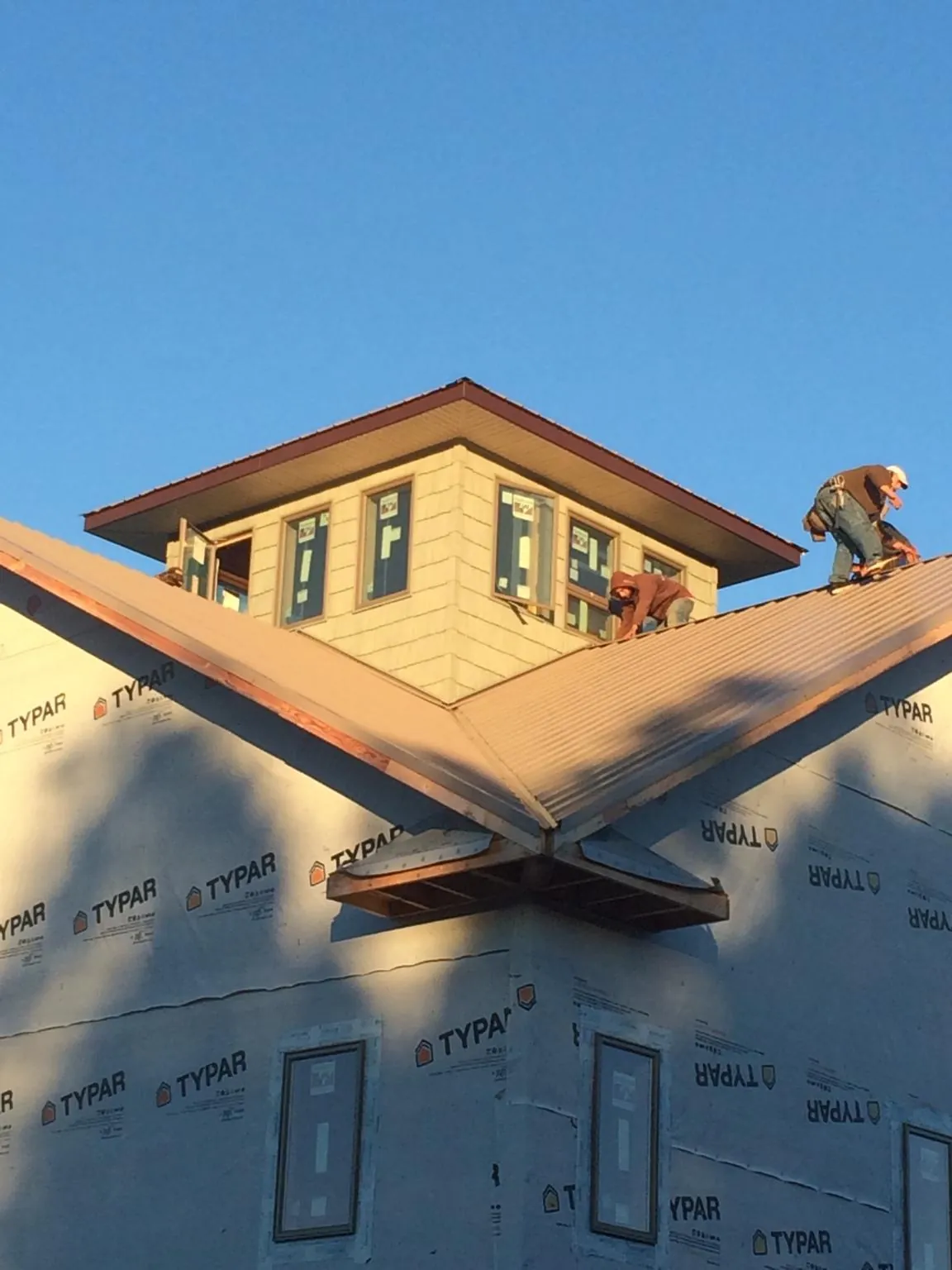 Roofers working around a rooftop cupola on a new metal roof at sunset — Roof Waterproofing in Melstone by Roofing Brothers